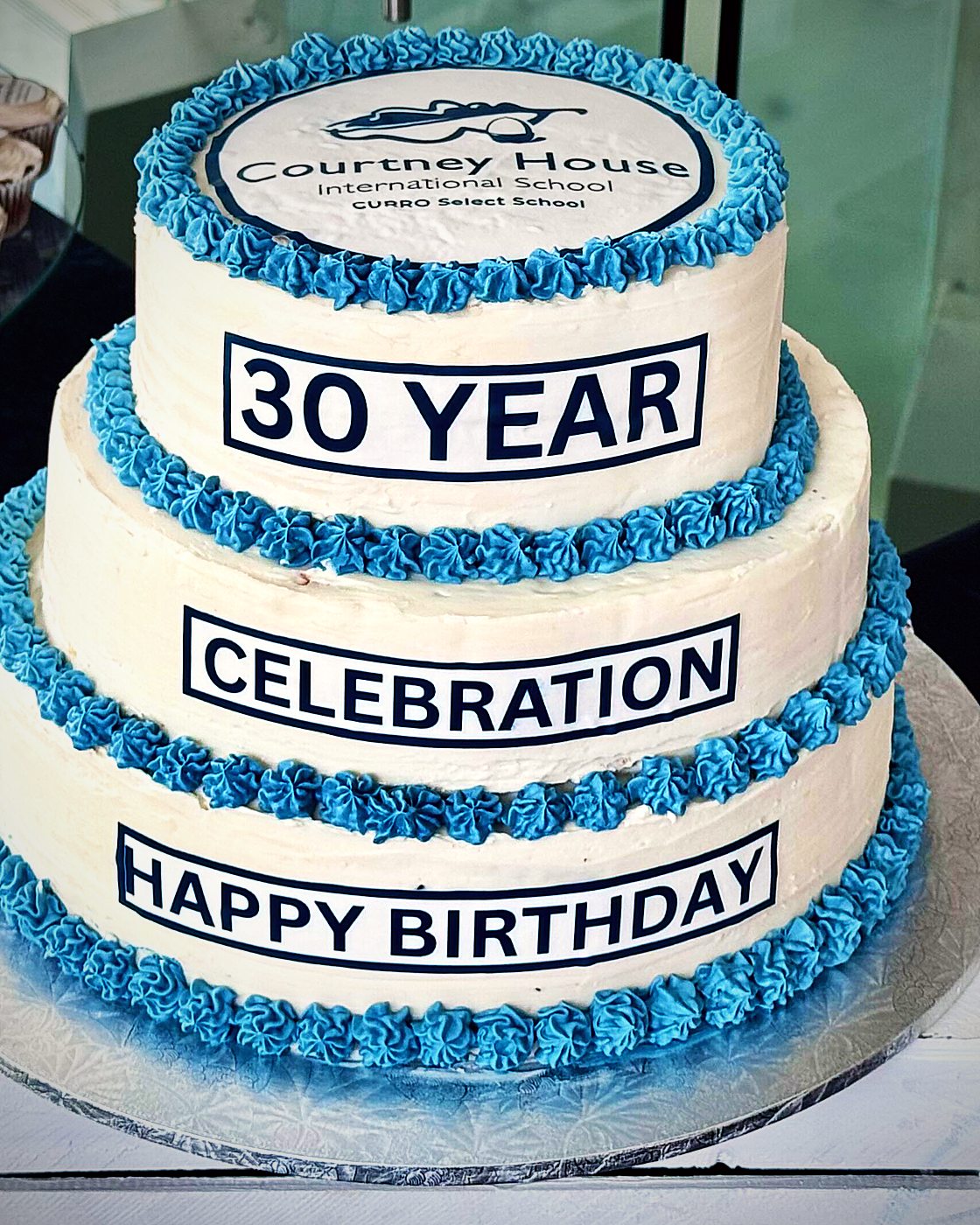 The three-tier blue and white cake for Courtney House International School's 30th Year Celebration