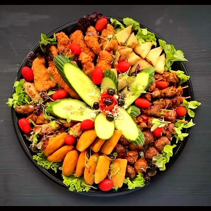 A round platter of samoosas, spring rolls and skewers