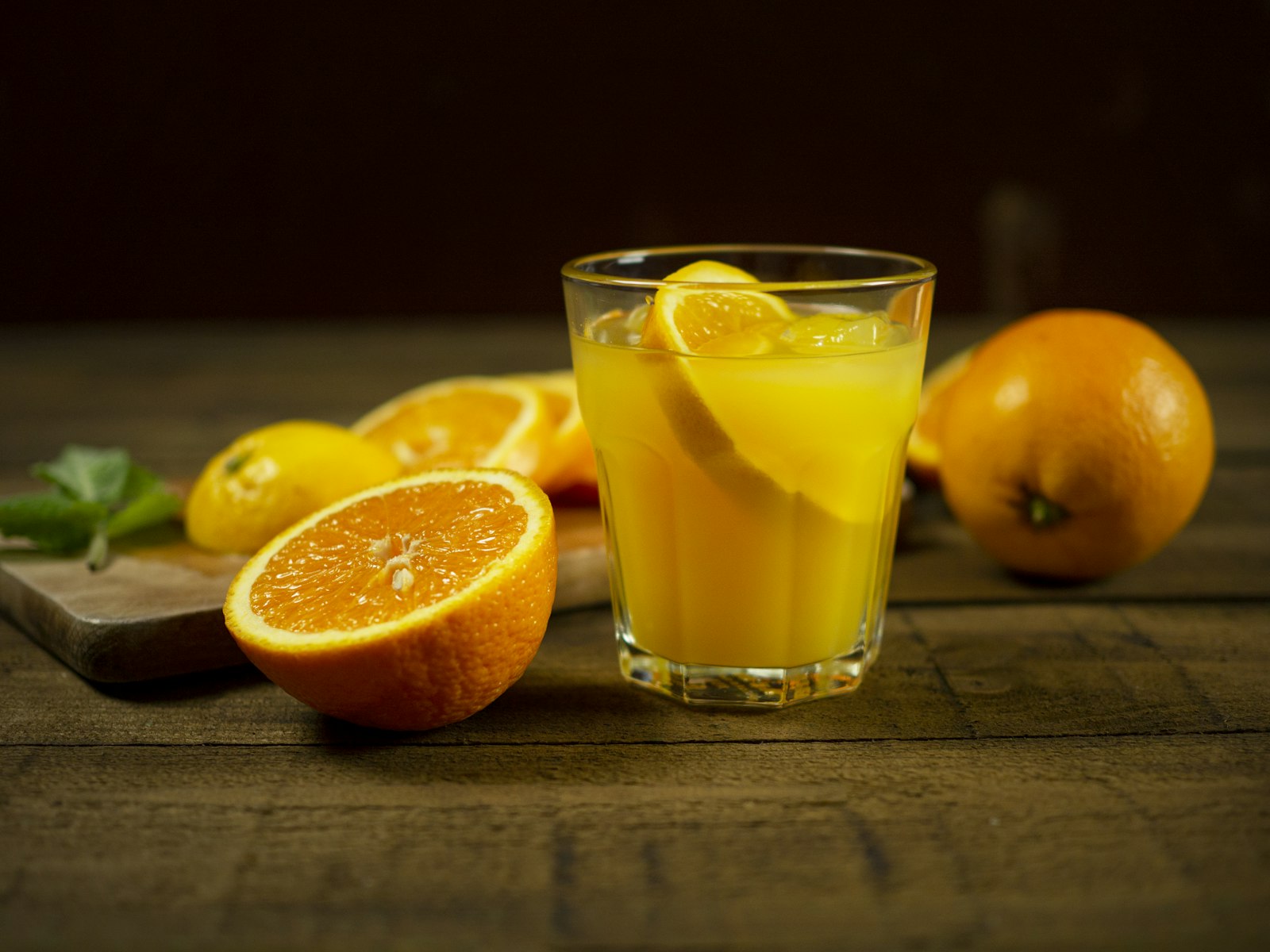 A glass of orange juice with oranges